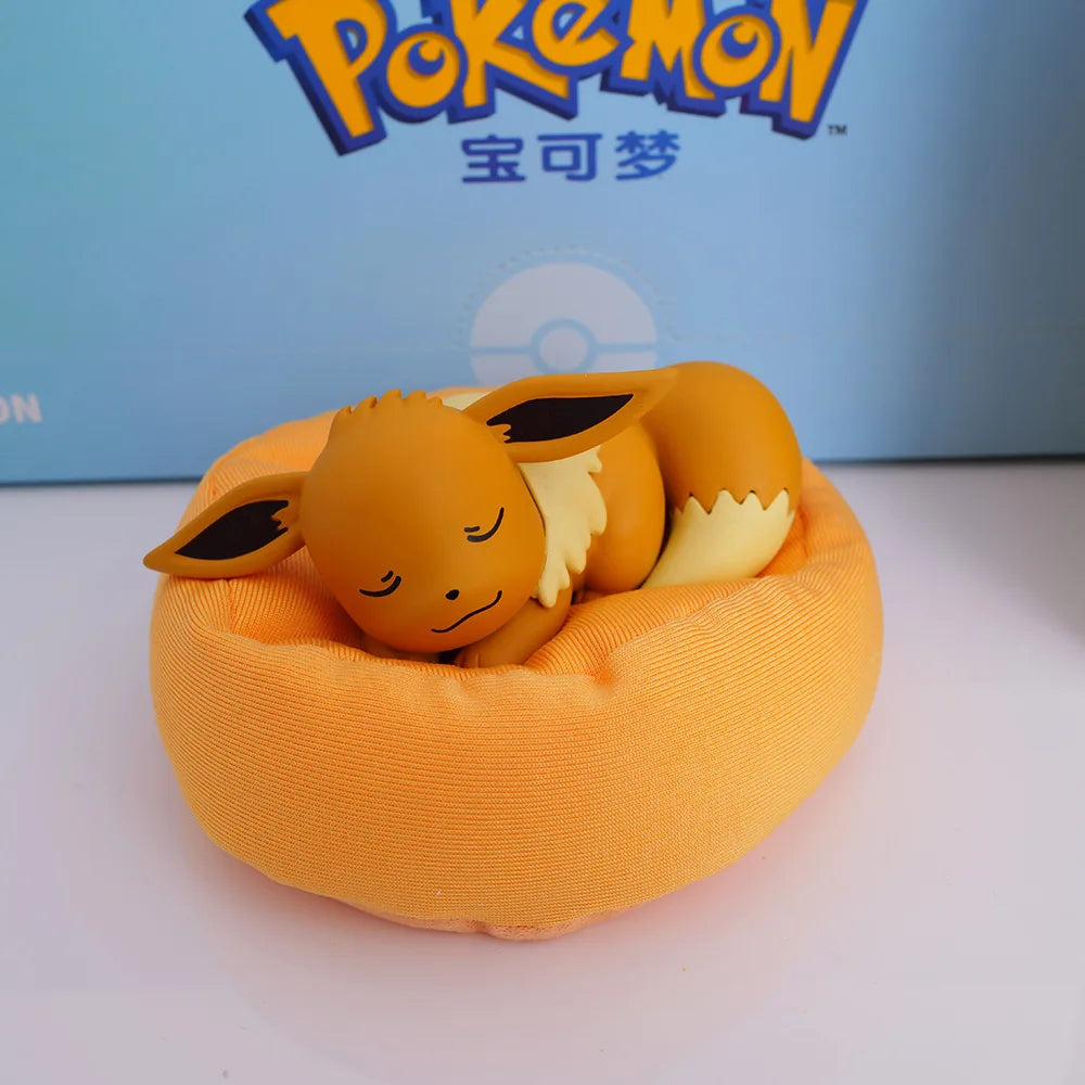Eevee figurine sleeping on an brown cushion/pillow, showcasing its adorable design, with a Pokémon-branded background.