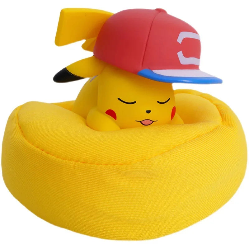 Pikachu figurine sleeping on a yellow cushion, wearing a red and blue cap, showcasing a charming Pokémon design.